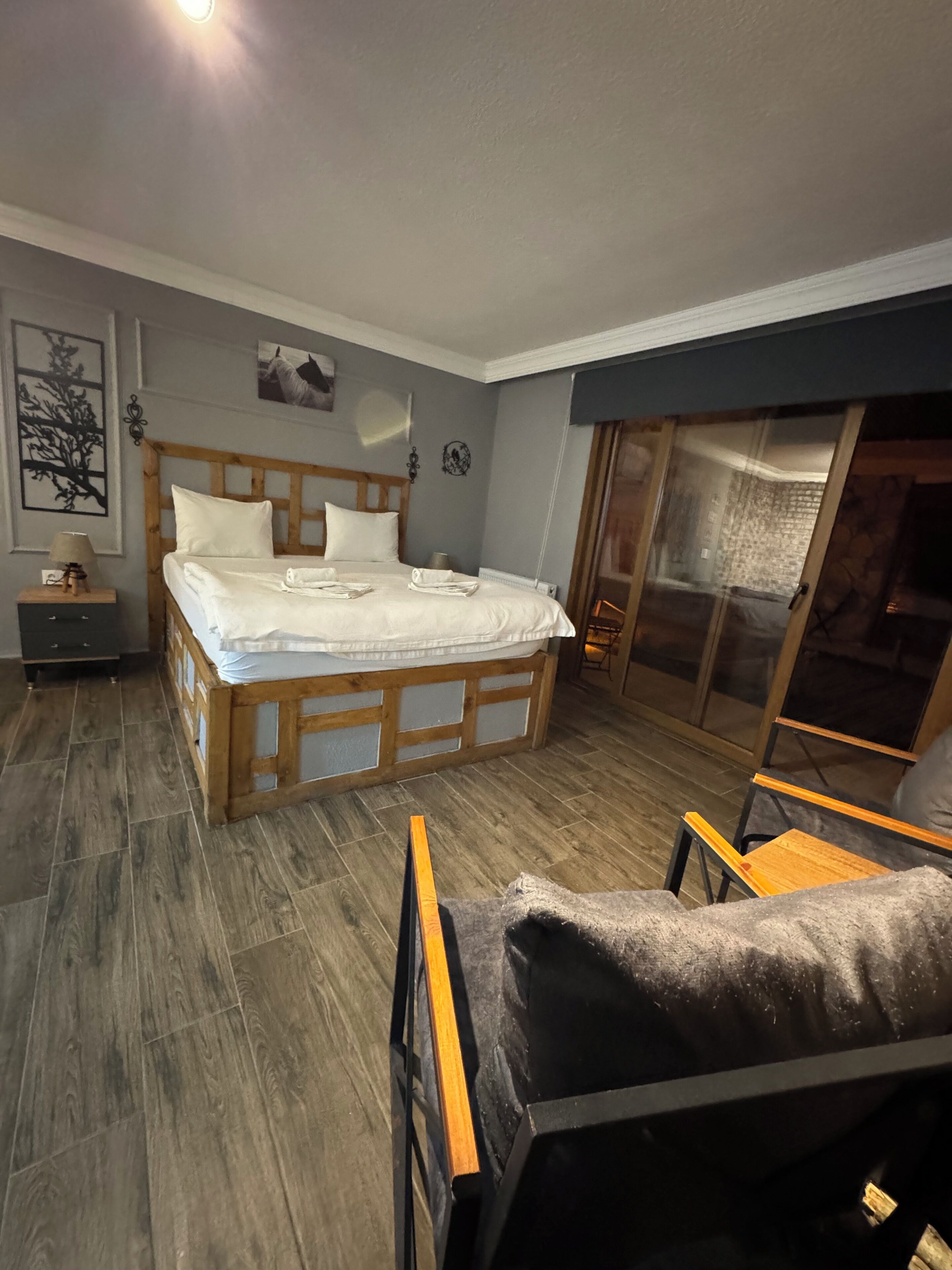 A bedroom with a wooden bed, a nightstand, a chair, and a sliding glass door to a balcony.