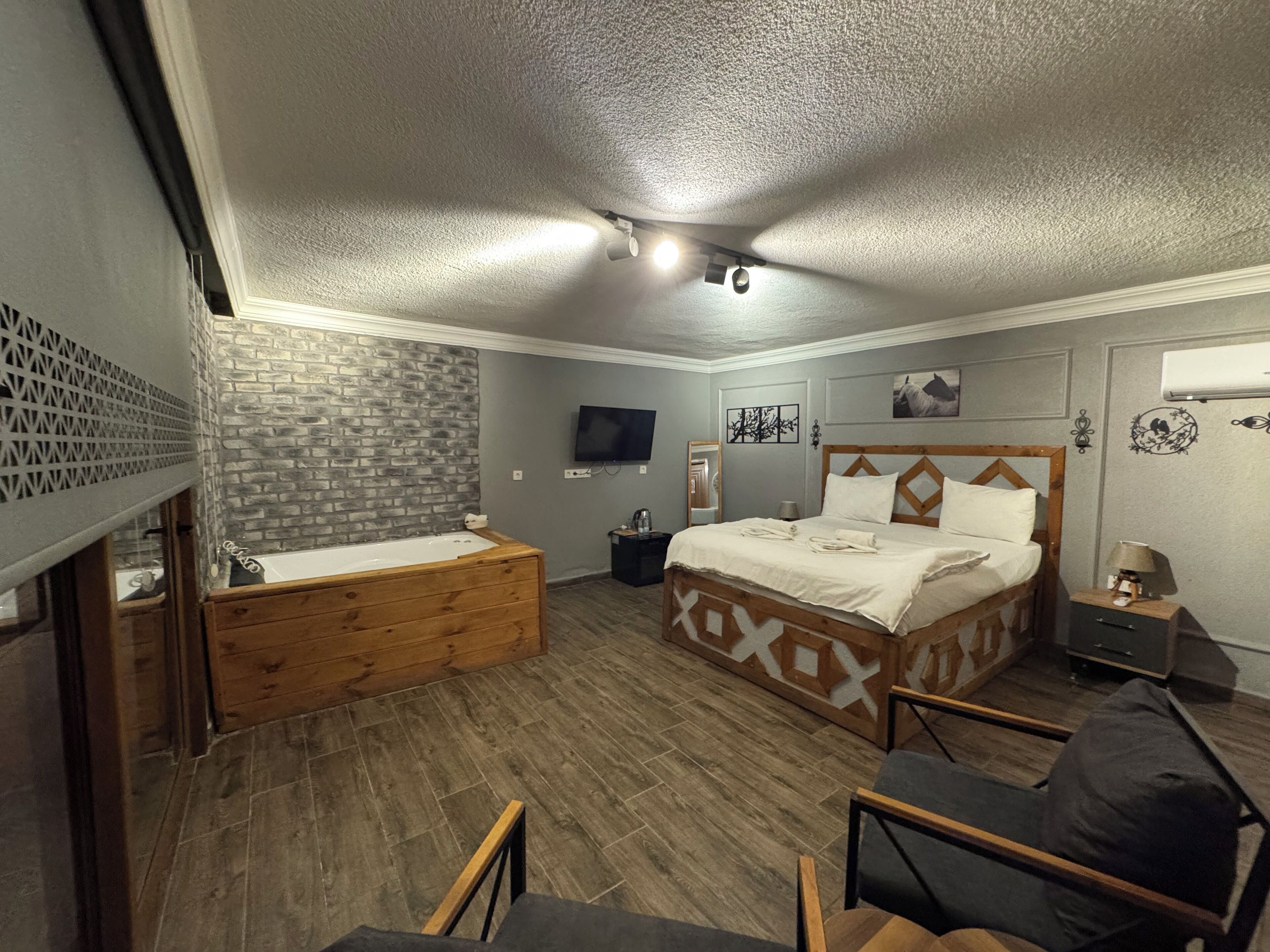 Une chambre avec un lit en bois, un banc en bois, une télévision et un radiateur fixé au mur.