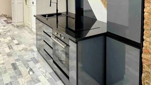 A modern kitchen with a black countertop, a built-in stove, and a stone accent wall.