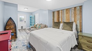 Ein Schlafzimmer mit Bett, Schminktisch, Kommode, Bücherregal und einer Tür.