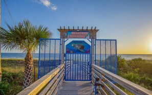 A wooden boardwalk leading to a gated entrance with a sign indicating a private beach. - Beach Better | Private Beach Access (Panama City Beach)
