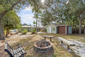 A backyard with a fire pit, benches, and a small shed. - Beach Better | Private Beach Access (Panama City Beach)
