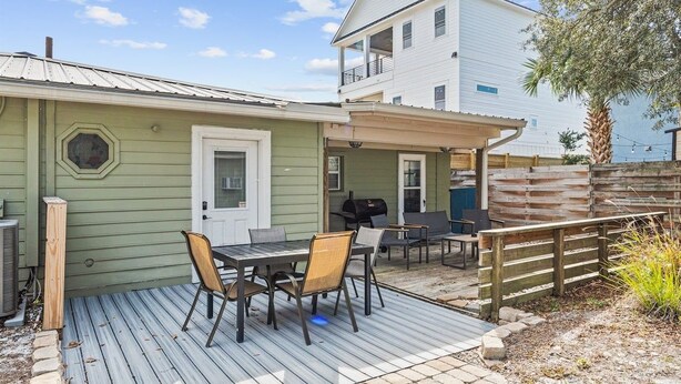 A patio with a table and chairs, a grill, and a wooden fence. - Beach Better | Private Beach Access (Panama City Beach)