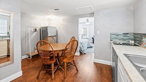 A compact kitchen with a dining area, wooden chairs, a refrigerator, and a dishwasher. - Beach Better | Private Beach Access (Panama City Beach)