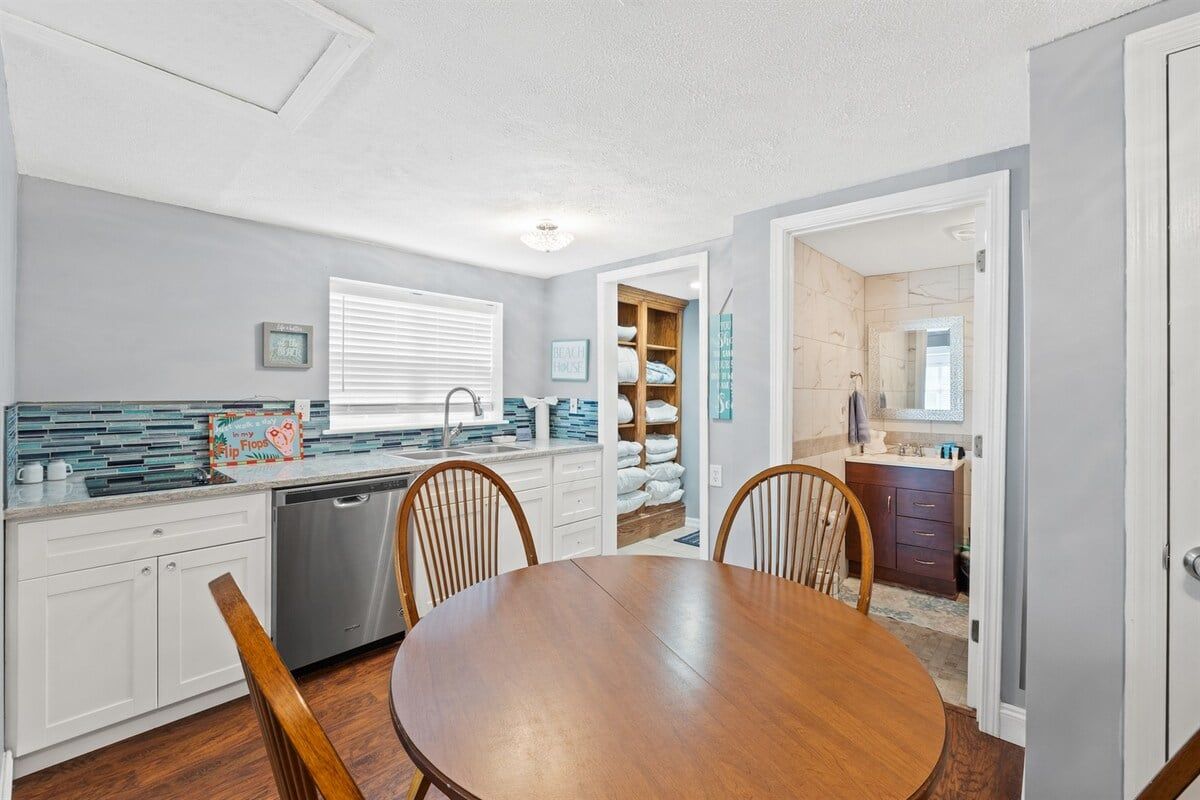 A modern kitchen with a dining table, chairs, and a built-in dishwasher.
