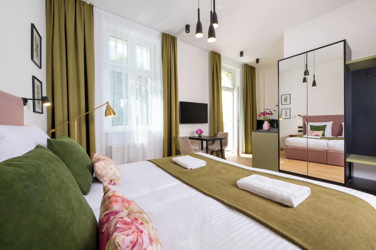 A hotel room with a large bed, a desk, a chair, a TV, and a mirror.