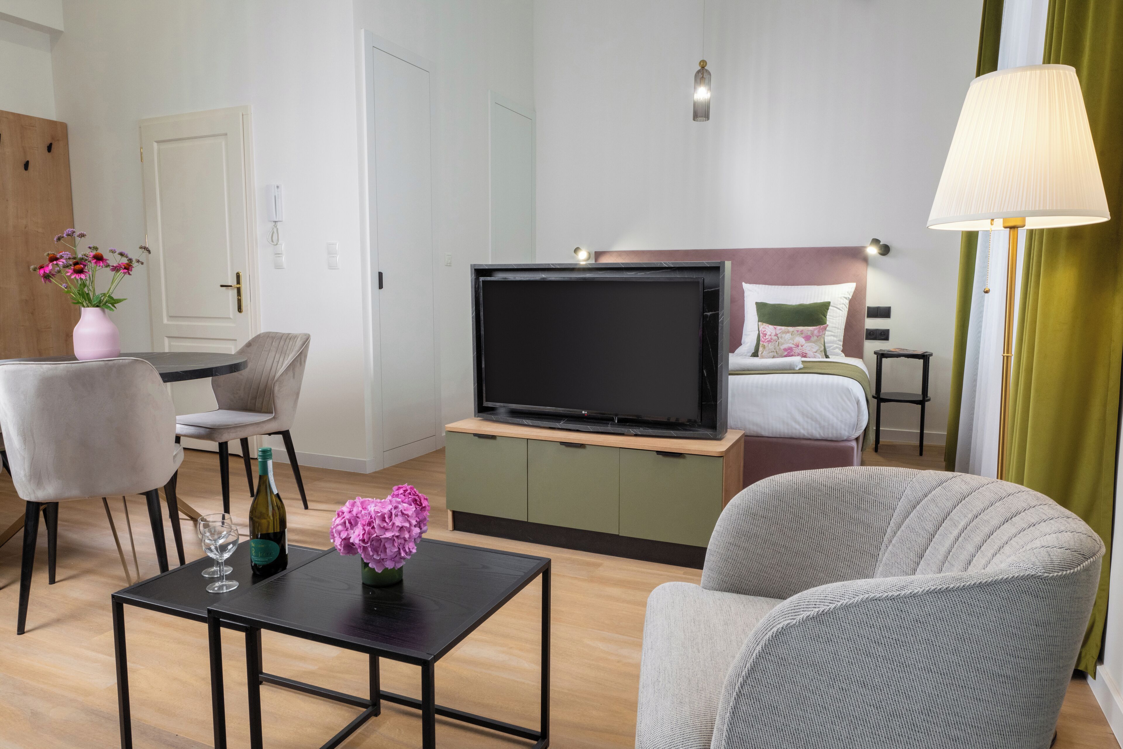 A modern hotel room with a TV, a bed, a desk, and a chair.