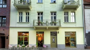 A multi-story building with a green facade, multiple balconies, and a ground-level cafe with outdoor seating. - Rajska Residence (Kraków)