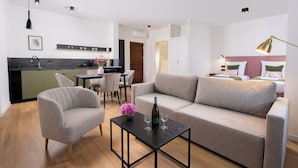 A modern living room with a sofa, a coffee table, and a dining area. - Rajska Residence (Kraków)