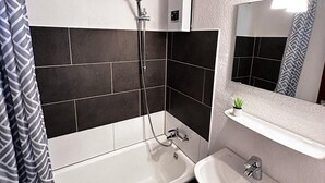 A modern bathroom with a bathtub, a sink, and a shower.