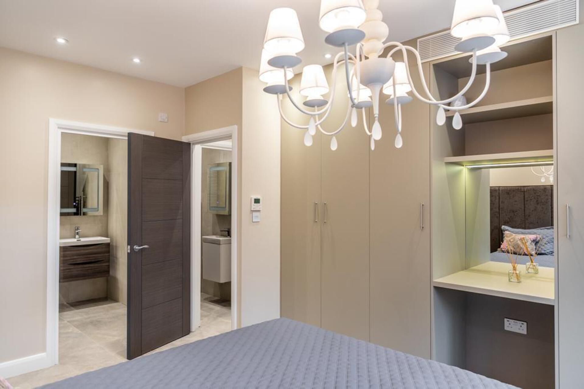 Een slaapkamer met een bed, een kledingkast, een spiegel en een kroonluchter.