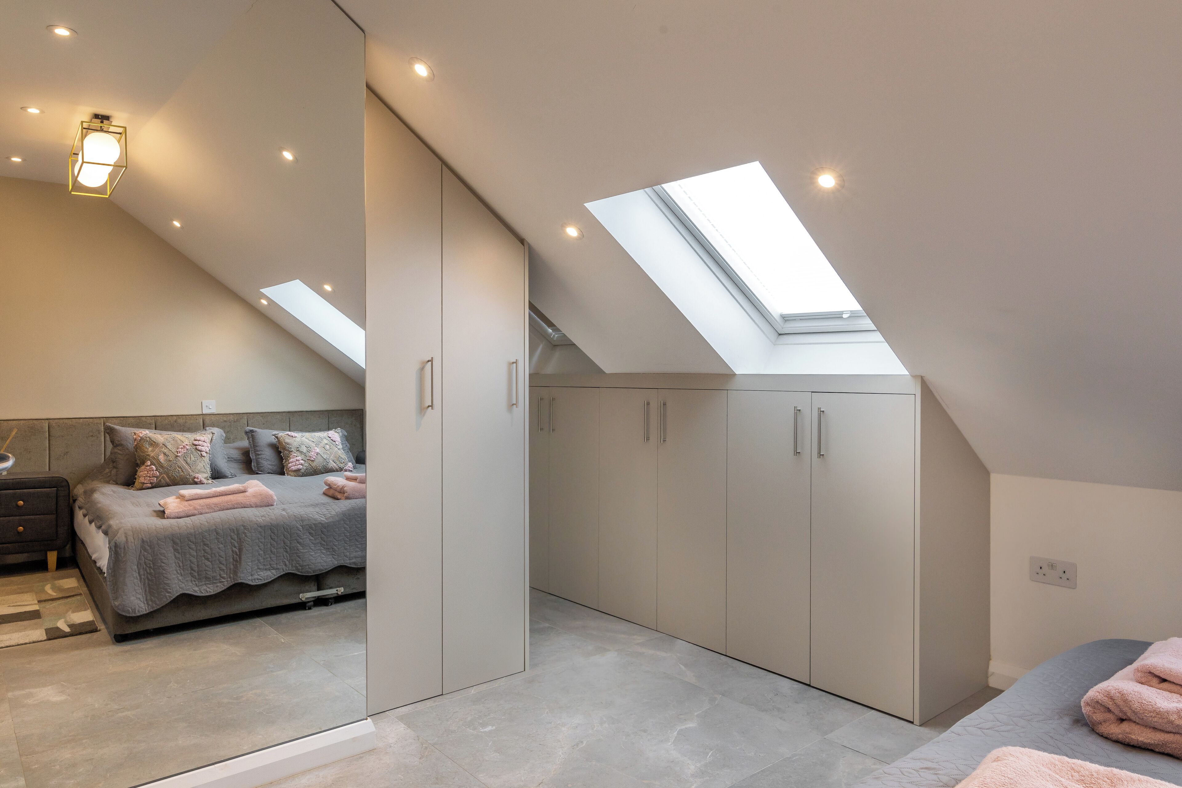 A bedroom with a skylight, a bed, and built-in wardrobes.