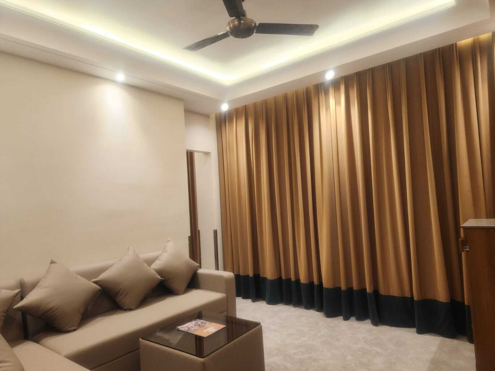 Un salon moderne avec un canapé beige, une table basse et un ventilateur de plafond.