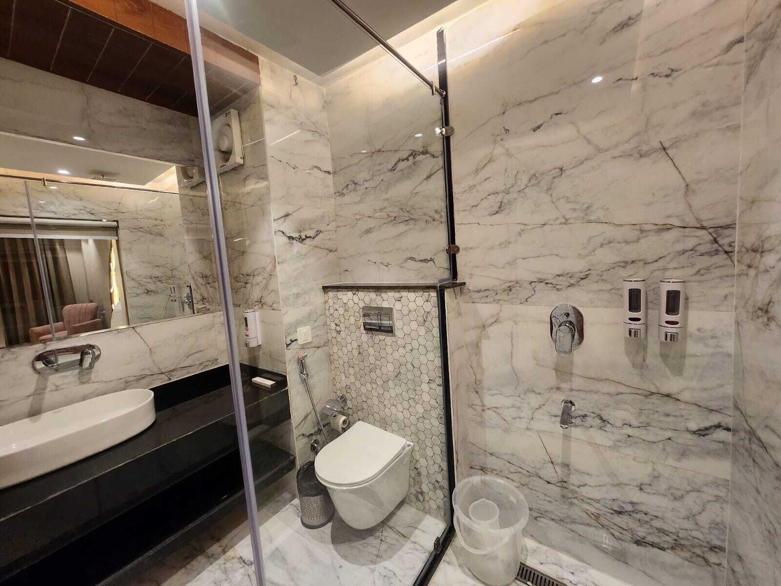Une salle de bain moderne avec une douche en marbre, des toilettes et un lavabo.