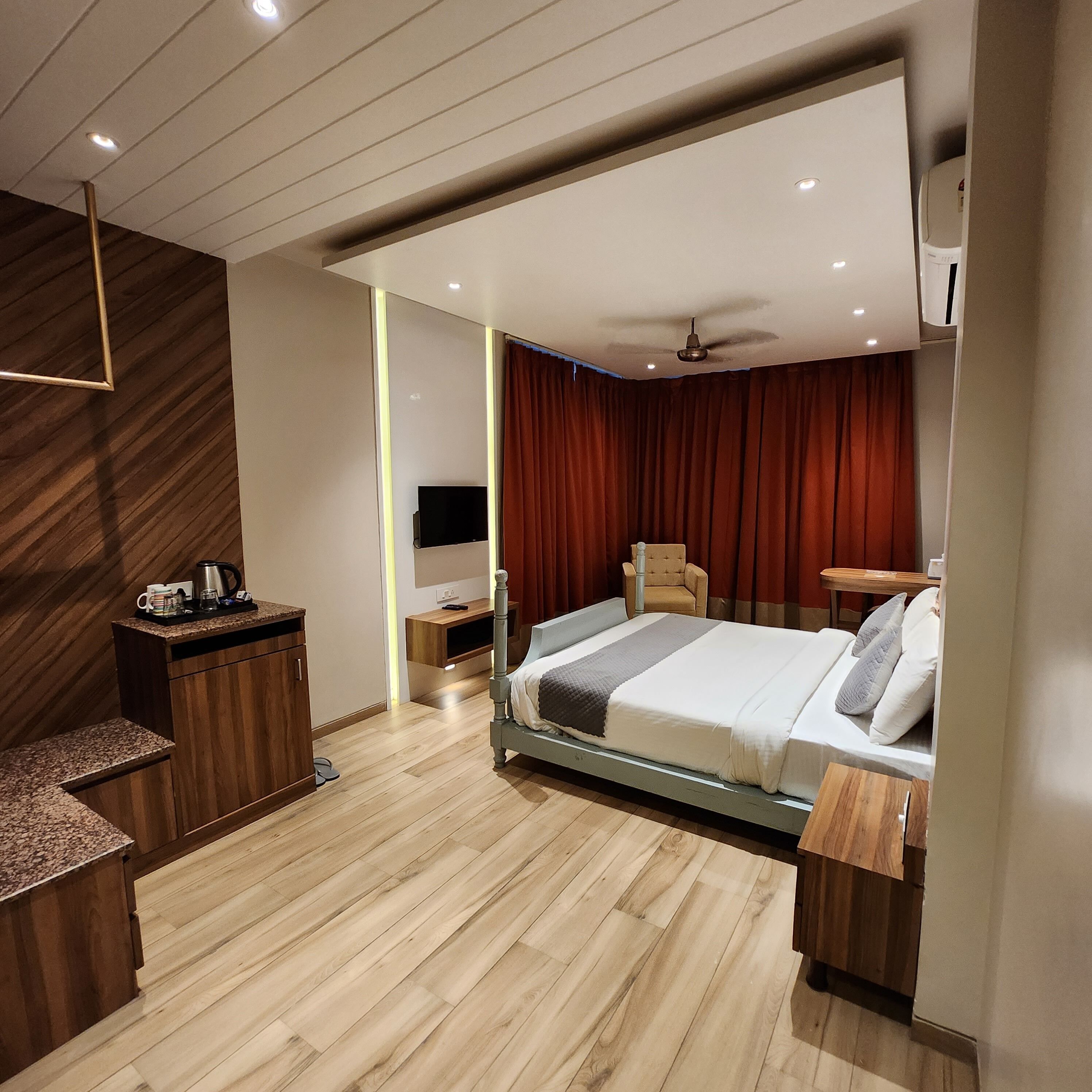 A modern hotel room with a bed, a desk, a chair, and a TV.