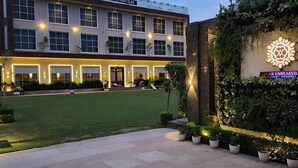 Um edifício de vários andares com uma placa que diz 'ALWAR VANYAEVILAS LUXURY RESORT'.