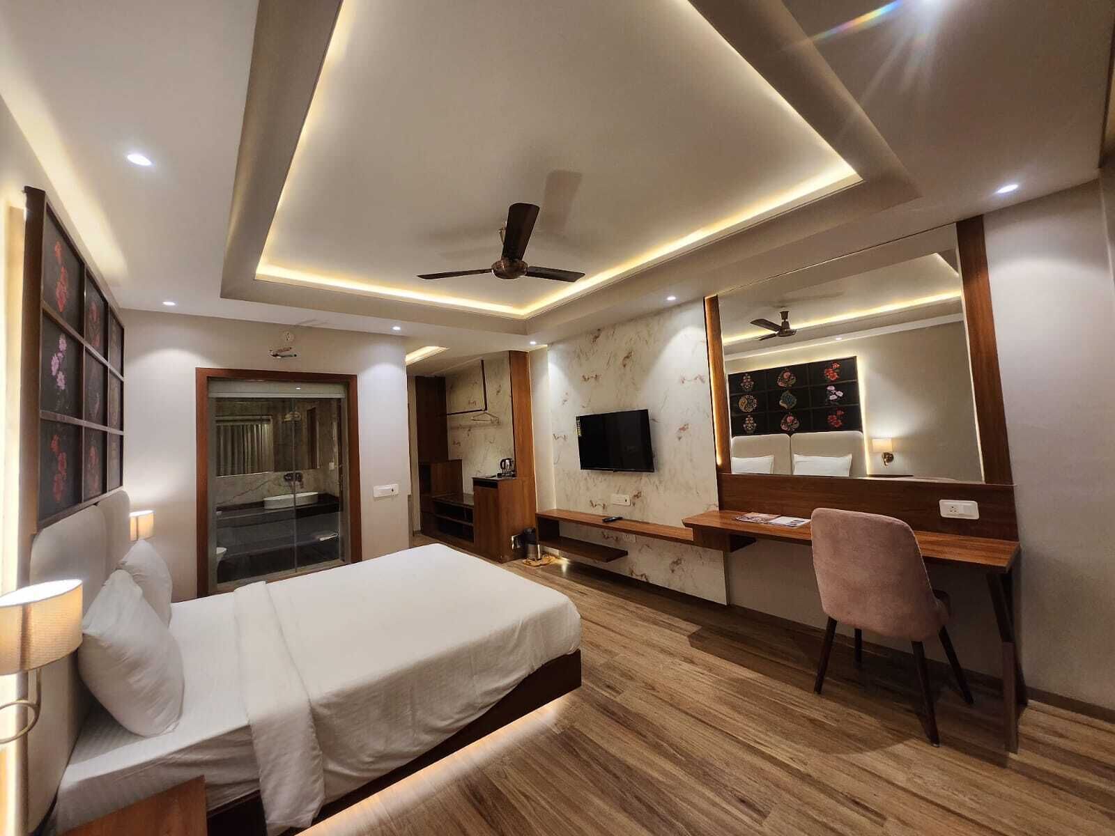 Una habitación de hotel moderna con cama, escritorio, silla, televisor y ventilador de techo.