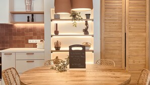 Eine moderne Küche mit einem runden Holztisch, Korbstühlen und Pendelleuchten.