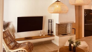 Ein modernes Wohnzimmer mit Flachbildfernseher, Korbmöbeln und Kamin.