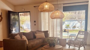 Ein modernes Wohnzimmer mit einer Eckcouch, einem runden Couchtisch und einem Korbstuhl.
