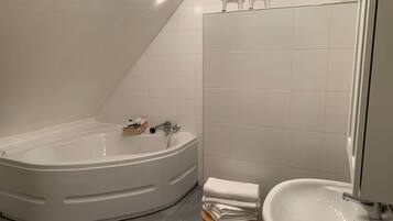 A modern bathroom with a freestanding bathtub, a sink, and a small stool.