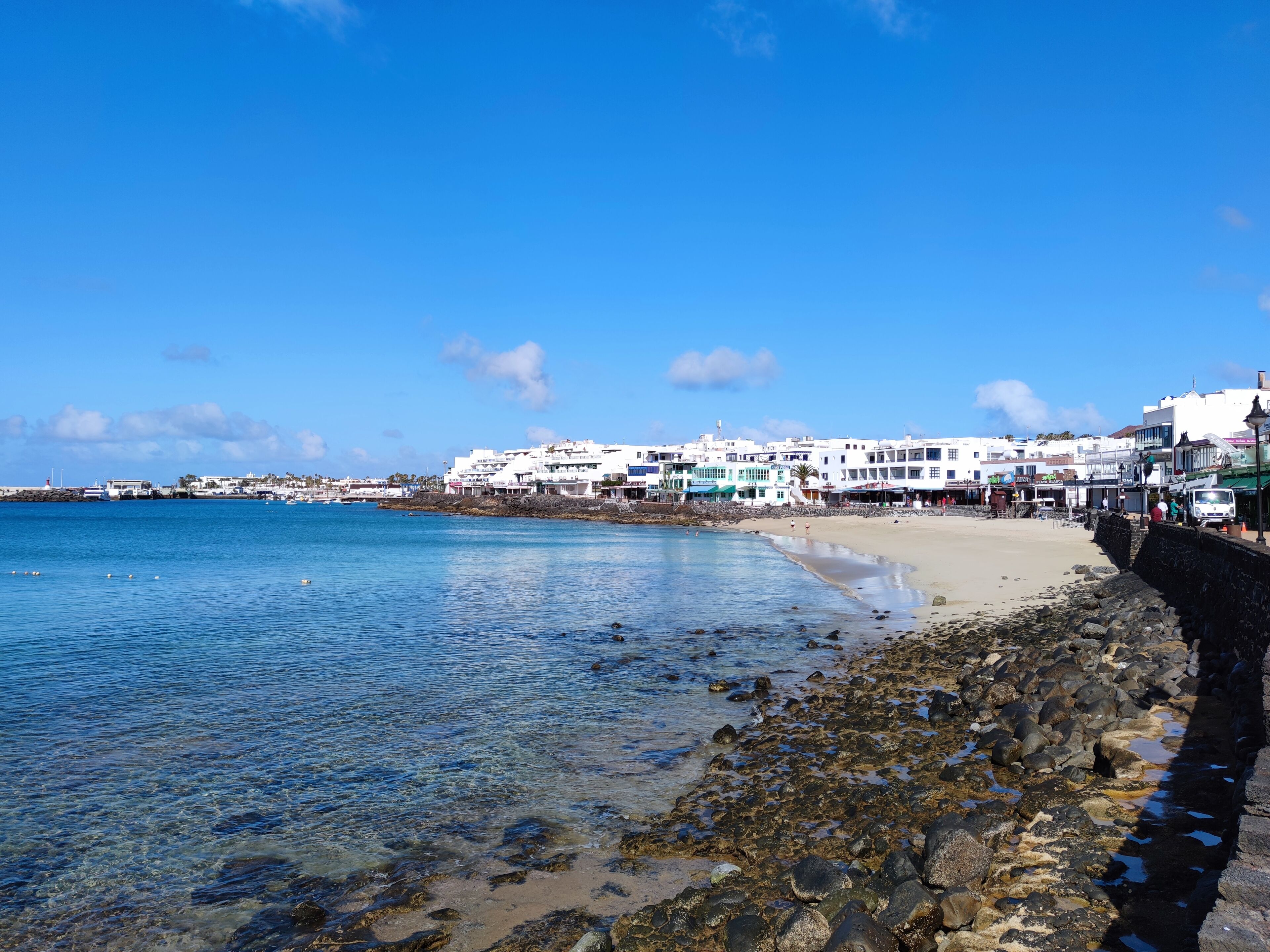 Un pueblo costero con edificios blancos, una playa de arena y agua azul cristalina.