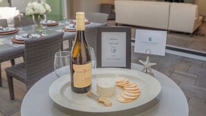 A dining table with a bottle of wine, cheese, crackers, and a framed welcome sign. - 3907 Twin Tides - Updated Beach House with Hot Tub (Carmel)