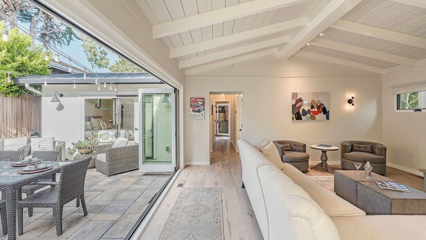A spacious living area with a large sofa, a dining table, and a kitchen visible through glass doors. - 3907 Twin Tides - Updated Beach House with Hot Tub (Carmel)