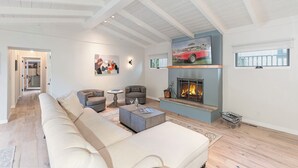 A spacious living room with a high ceiling, a fireplace, and a large window. - 3907 Twin Tides - Updated Beach House with Hot Tub (Carmel)