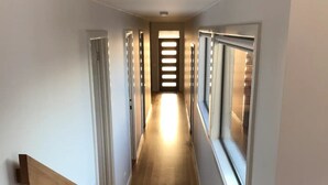 Ein Flur mit Holzboden, weißen Wänden und einer Treppe zu einer Zwischenebene.