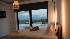 Ein Schlafzimmer mit einem großen Bett, Landschaftblick und einem Stuhl vor dem Fenster.