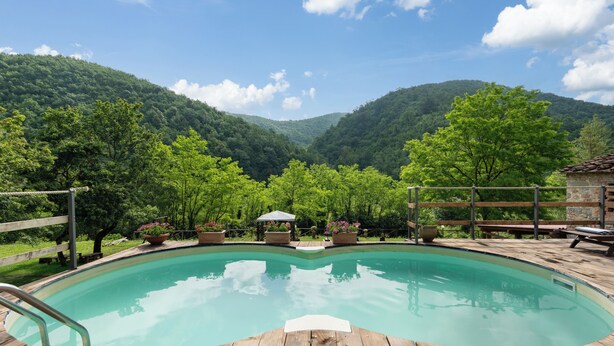 A wooden deck surrounding a swimming pool with a mountain backdrop. - Locanda Di Alberi (Borgo San Lorenzo)