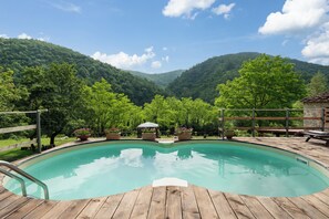 A wooden deck surrounding a swimming pool with a mountain backdrop.