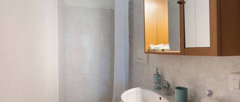 A modern bathroom with a shower, toilet, sink, and mirror.