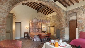 A rustic room with a four-poster bed, a dining table set with breakfast, and a cozy seating area. - Locanda Di Alberi (Borgo San Lorenzo)