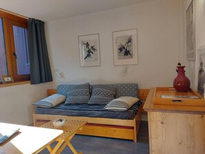 A cozy room with a wooden sofa, a small table, and a red vase on a wooden cabinet. - 6th floor, view forest, tv, 13m², Les Arcs (Les Arcs)
