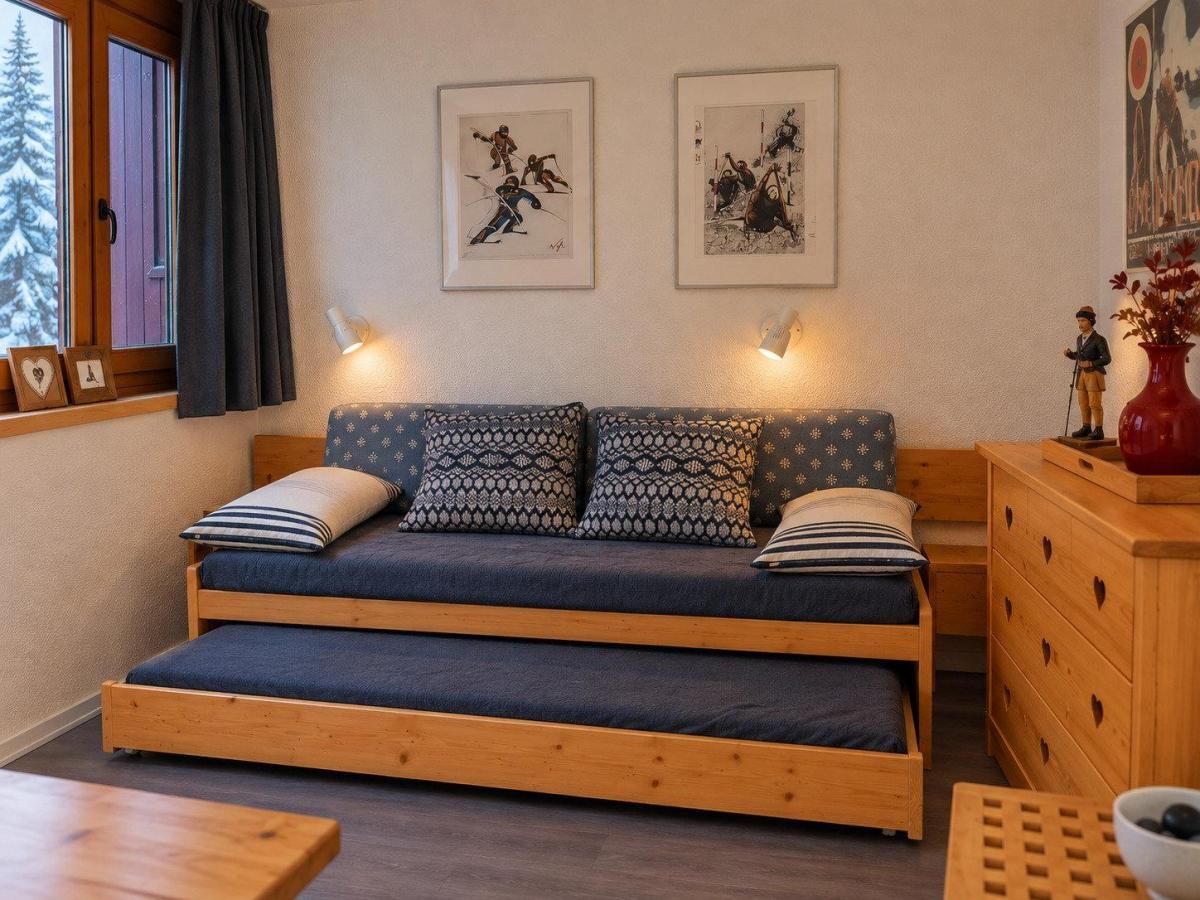 Una habitación acogedora con una cama de madera, un aparador y dos cuadros en la pared.