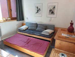 A single bed with a wooden frame, a small bedside table, and a red vase. - 6th floor, view forest, tv, 13m², Les Arcs (Les Arcs)
