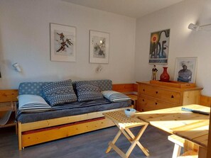 A cozy room with a sofa, a small table, and a wooden dresser. There are framed pictures on the wall. - 6th floor, view forest, tv, 13m², Les Arcs (Les Arcs)