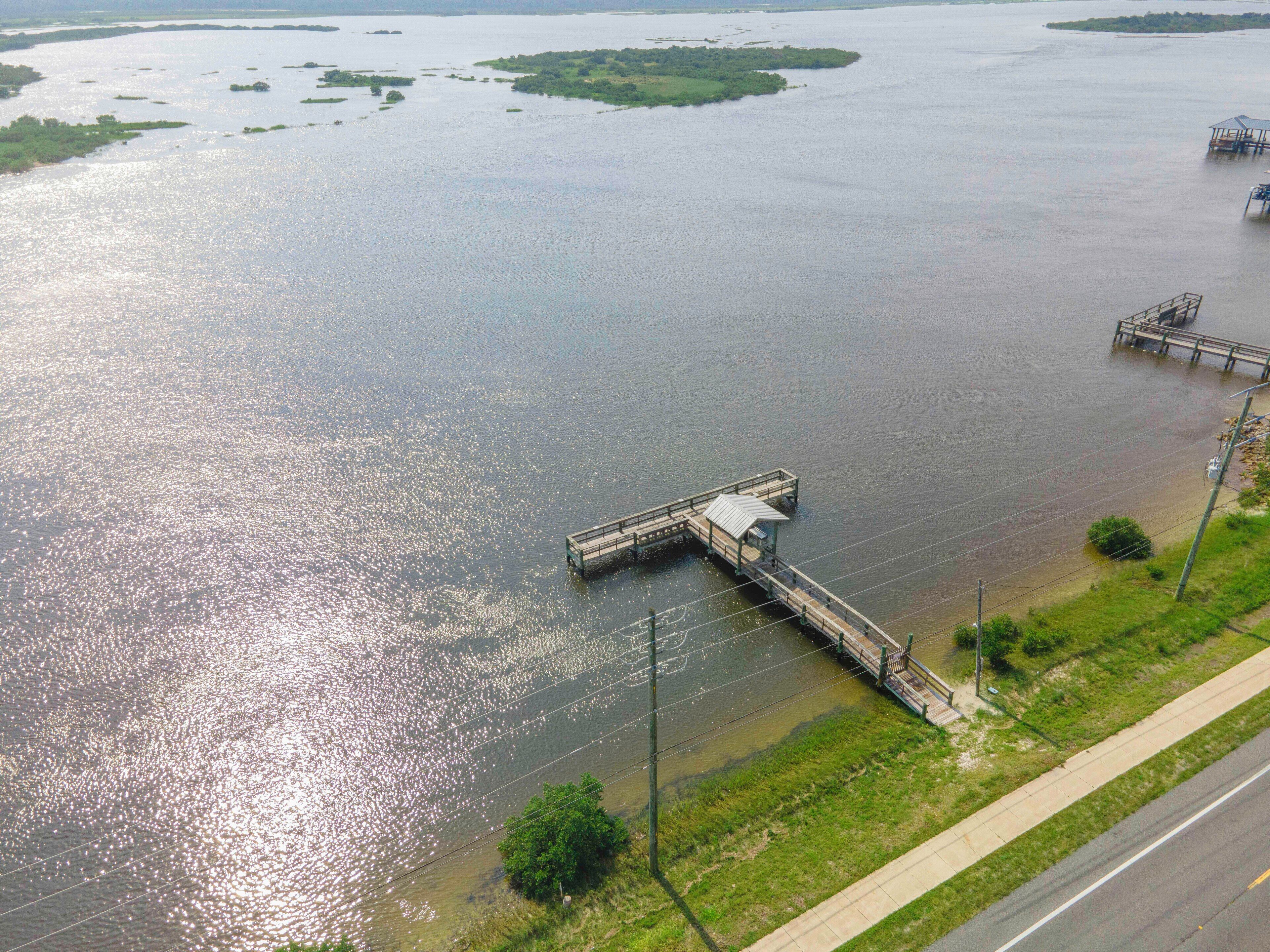 A river with a bridge and a dock extending into the water.