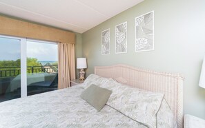 A bedroom with a large bed, a balcony with a view, and decorative wall art. - Wonderful oceanfront condo with Intercoastal Views! (Saint Augustine)