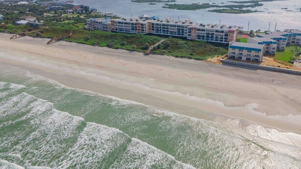Ein Küstenhotel mit mehreren Gebäuden, einem Strand und Blick aufs Meer.