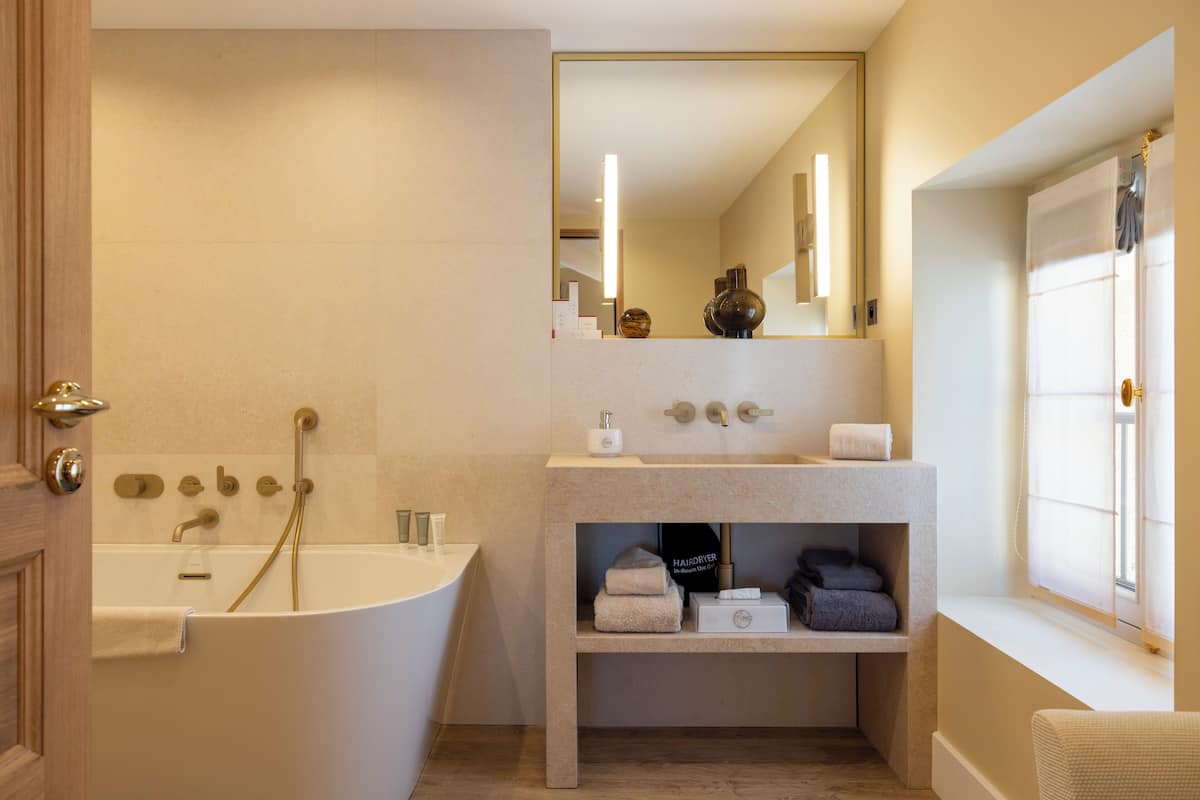 Un bany modern amb una banyera autònoma, un lavabo amb mirall i una estant amb tovalloles i productes de tocador.