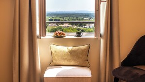 Ein Fensterplatz mit Kissen, ein Teller mit einem Croissant und eine Tasse auf dem Fensterbrett.