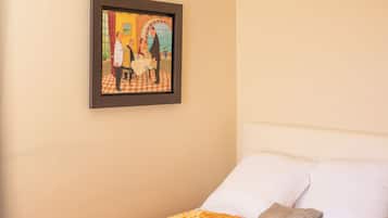 Une chambre d’hôtel avec un lit, un tableau encadré au mur et un sol à carreaux.