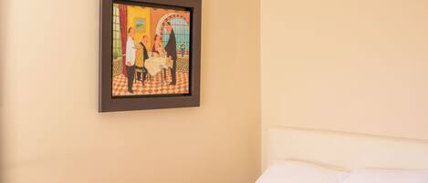 A hotel room with a bed, a framed picture on the wall, and a checkered floor.