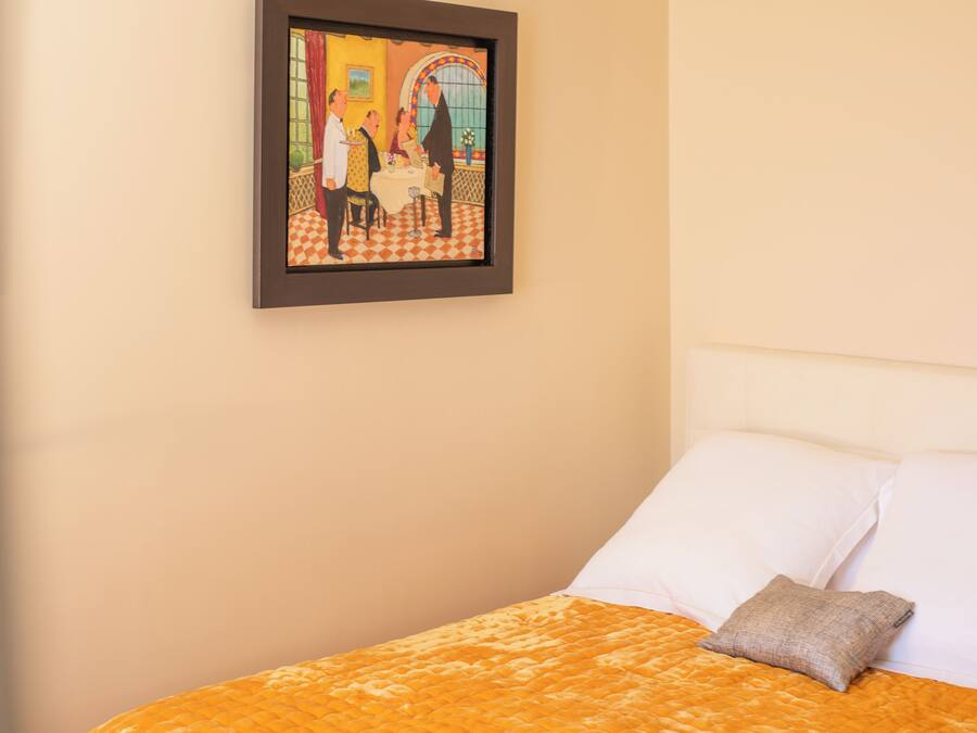 A hotel room with a bed, a framed picture on the wall, and a checkered floor.