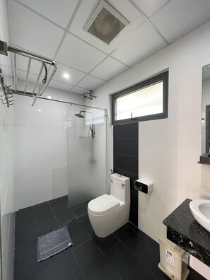 Une salle de bain moderne dotée d’une douche à parois de verre, de toilettes et d’un lavabo avec un plan de travail en marbre.