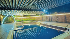Une piscine intérieure avec un bord carrelé, une échelle en métal et un plafond orné de lignes parallèles.