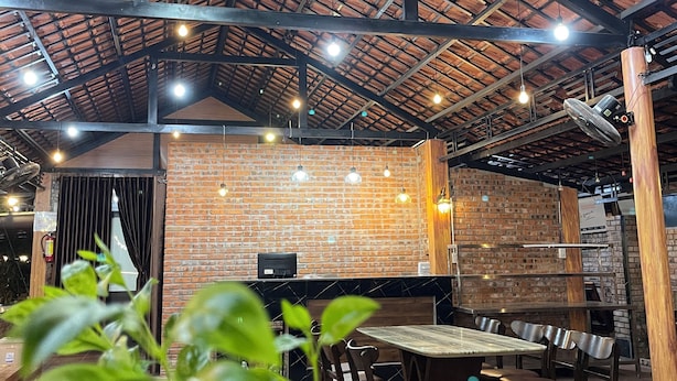 Un espace de restauration intérieur avec des murs en briques, des poutres apparentes au plafond et des luminaires suspendus.